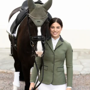 A woman in green jacket standing next to horse.
